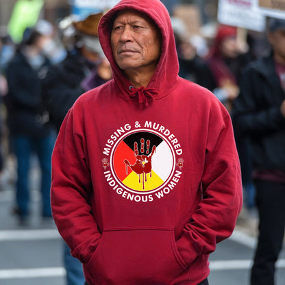 a man in a red hoodie stands in front of a crowd